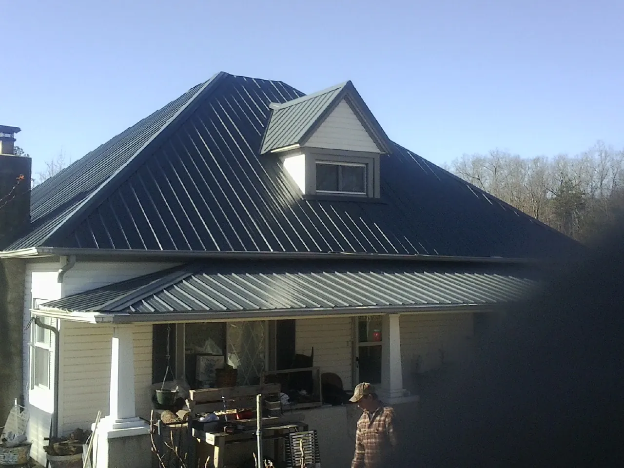 Dark blue standing seam metal roof with a dormer above a front porch in Baldwin City