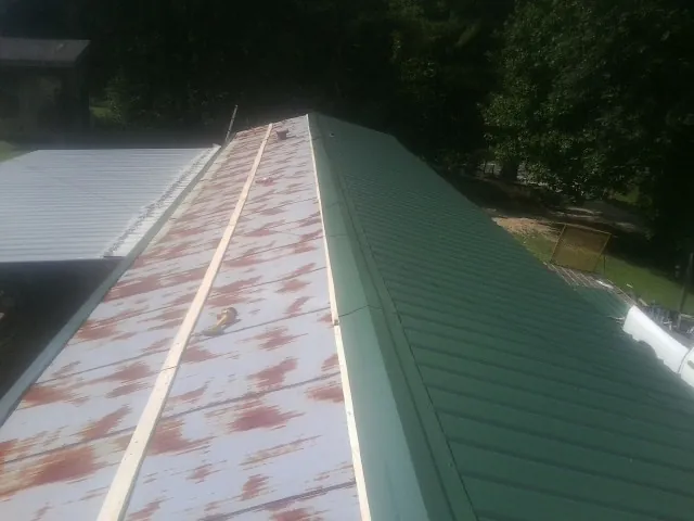 Old rusted panels beside newly installed green metal roofing — Wind Damage Roof Repair by Roofing Brothers in Baldwin City