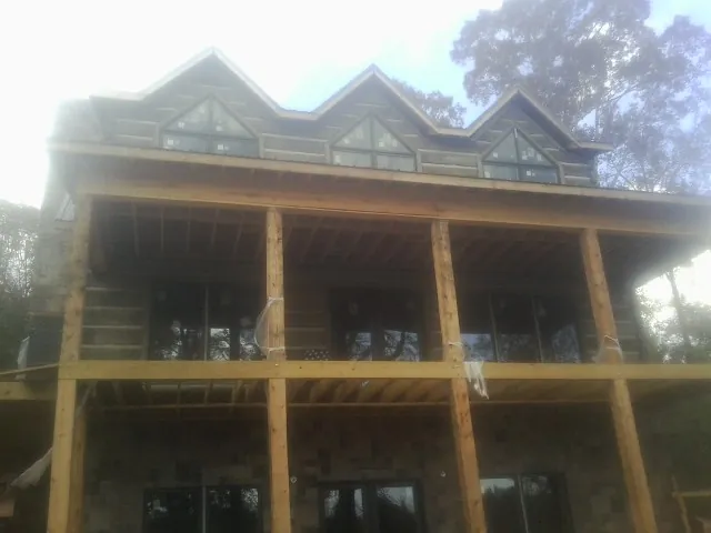 Dormers and porch framing on a large log home under construction — Roof Coating work by our crew in Baldwin City