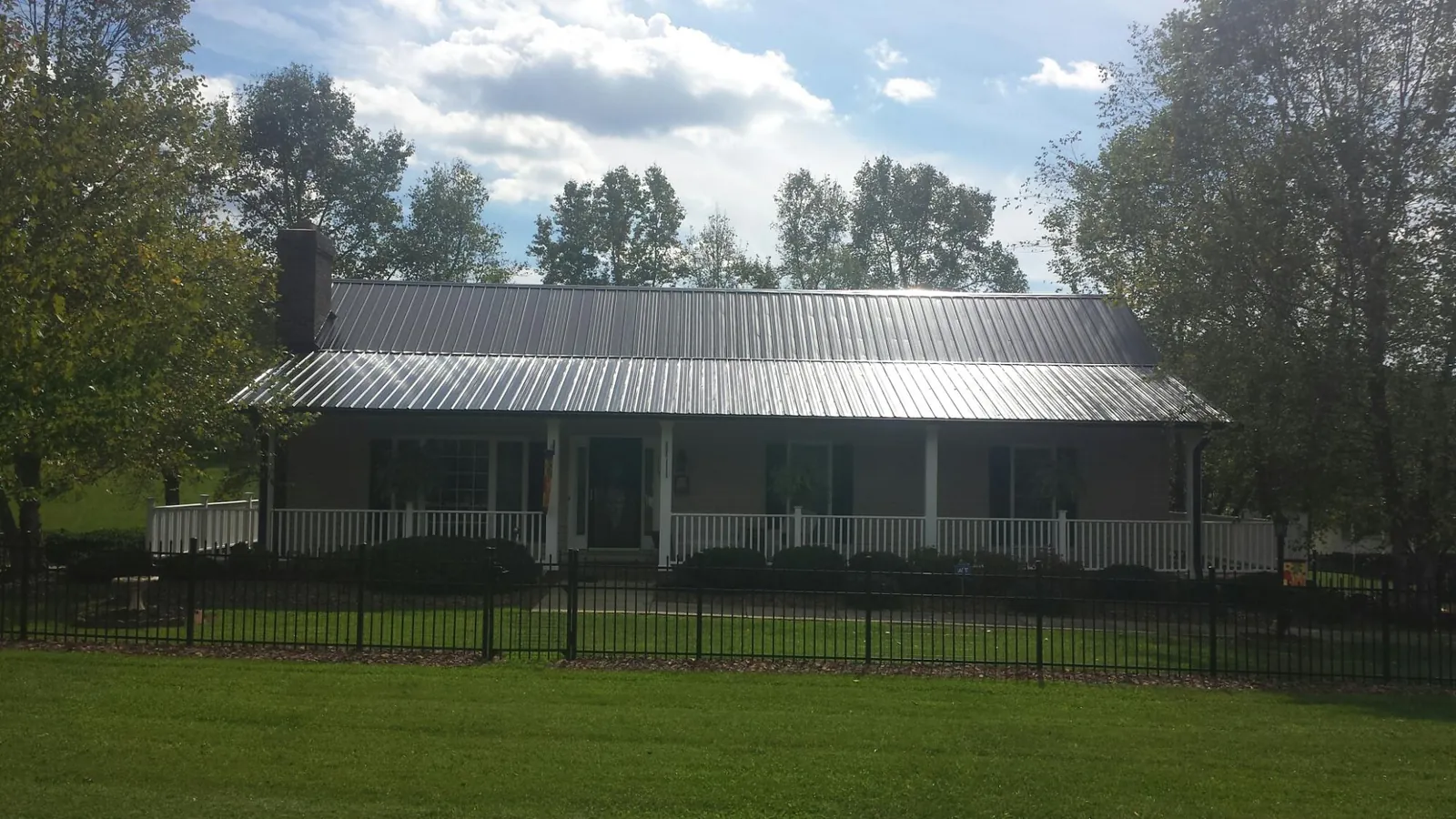 Gray metal roof on a brick ranch with a full width front porch — Gutter Guard Installation work by our crew in Baldwin City