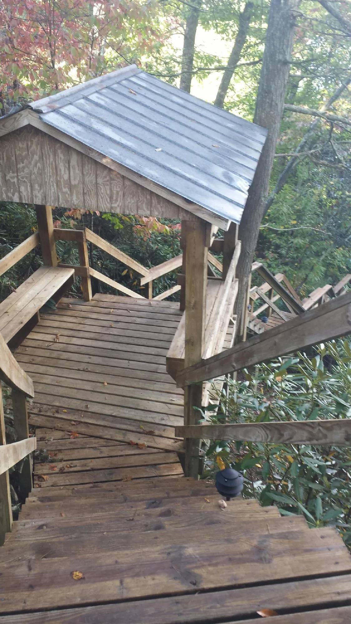Metal roofed shelter over wooden steps on a wooded walkway — Skylight Repair & Installation work by our crew in Baldwin City