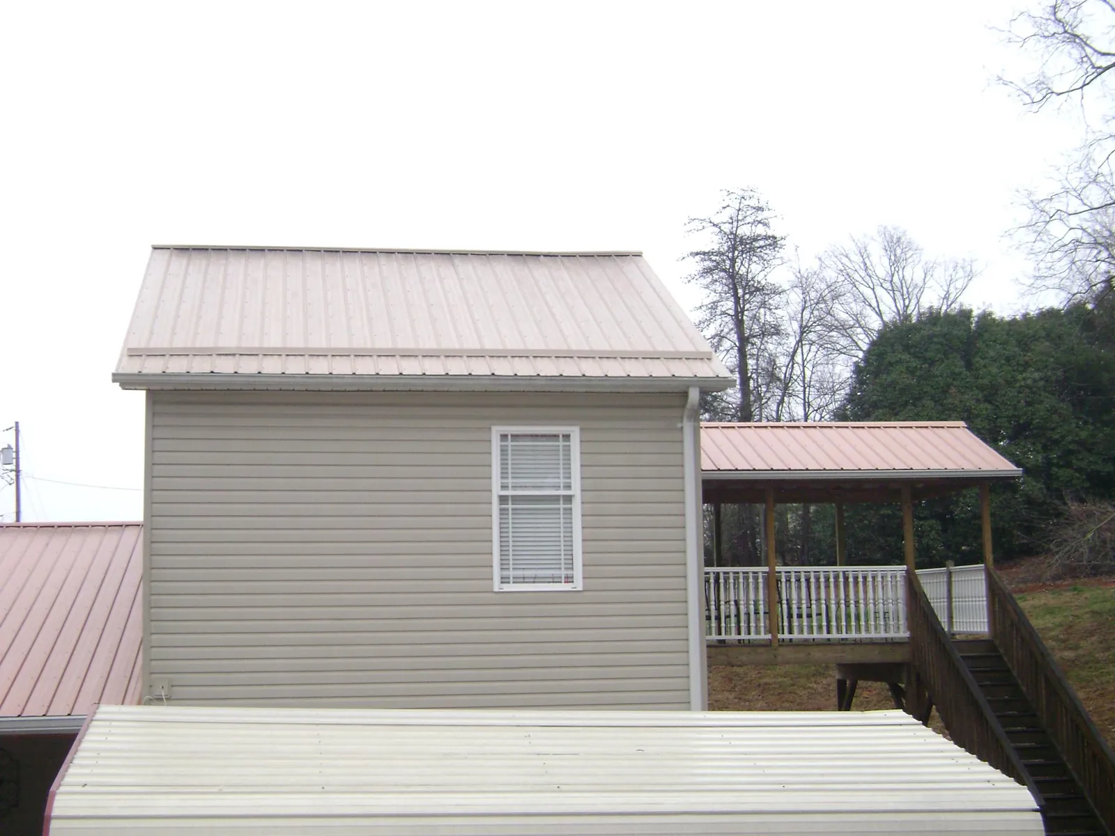 Tan metal roofs on a two story addition and attached porch, from a Roof Replacement job in Baldwin City