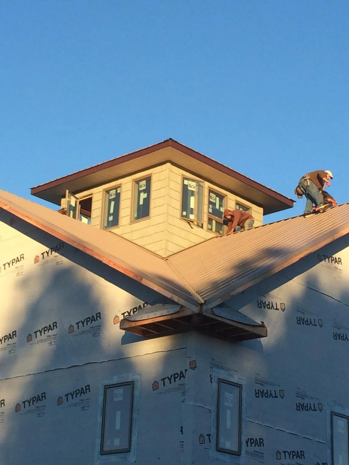 Roofers working around a rooftop cupola on a new metal roof at sunset — Roof Waterproofing in Baldwin City by Roofing Brothers